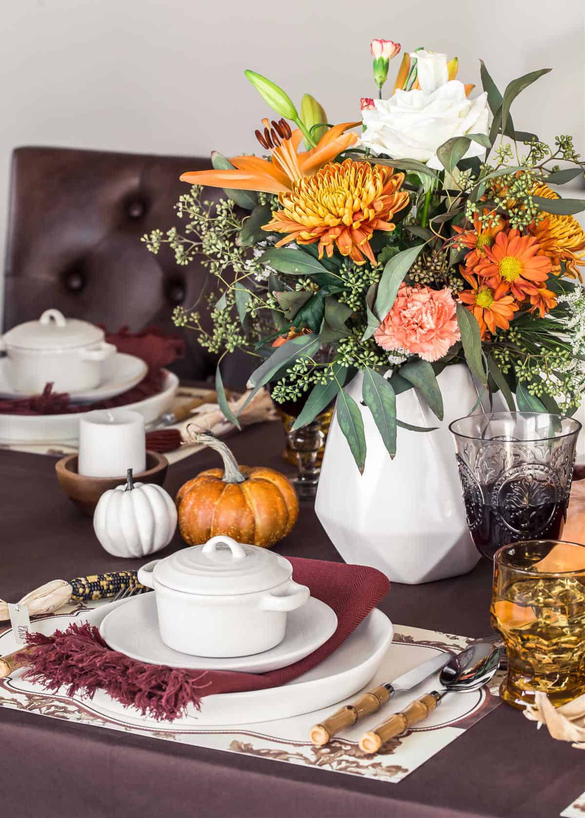 fall table setting with white dishes on brown table cloth