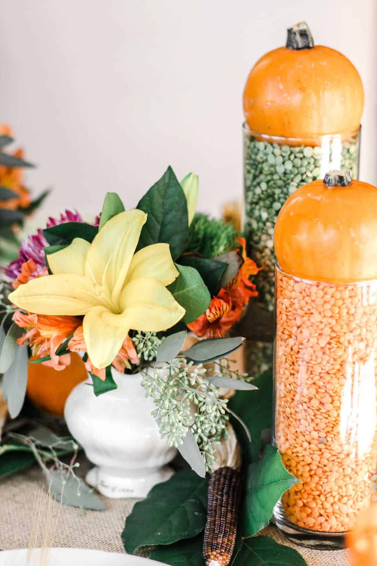 tall glass vases filled with colorful dry lentils and topped with mini pumpkins