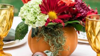 fall flowers in pumpkin vase on dining table outdoors