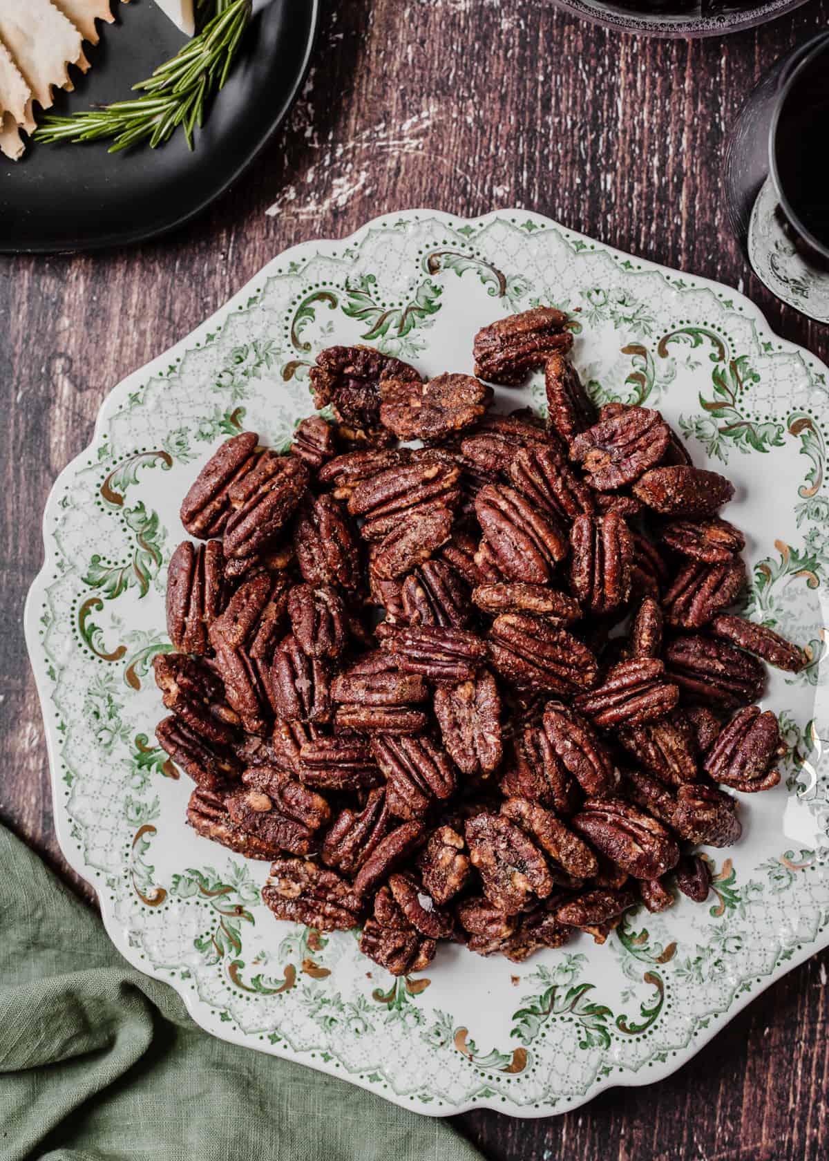 seasoned pecans served on vintage green and white plate on dark wood surface.