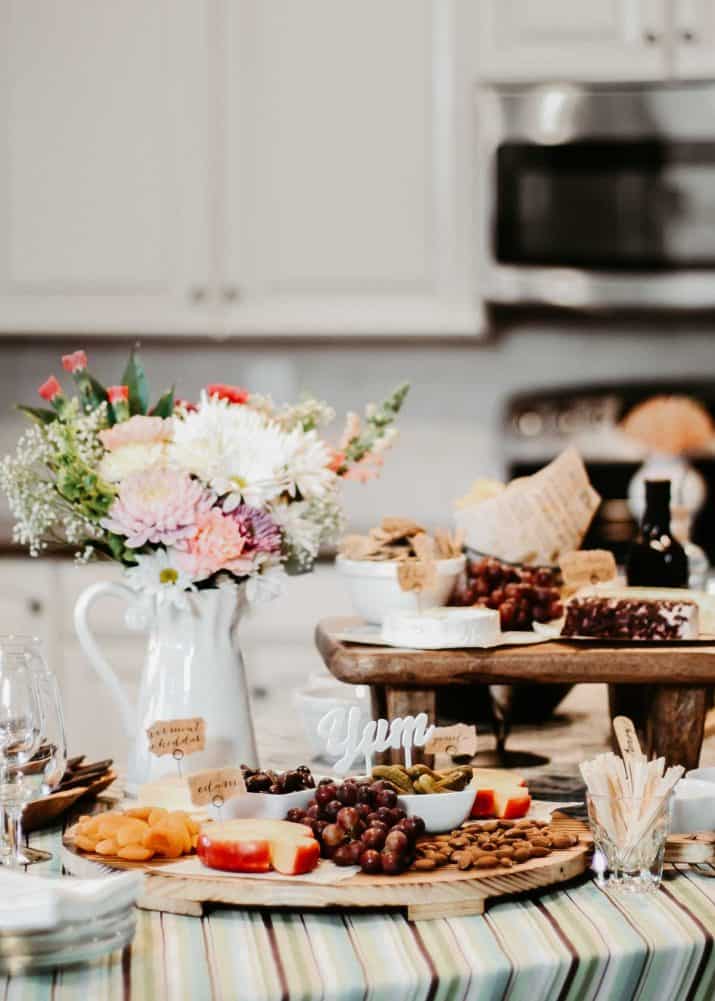 wine and cheese party foods and flowers set up on kitchen island.