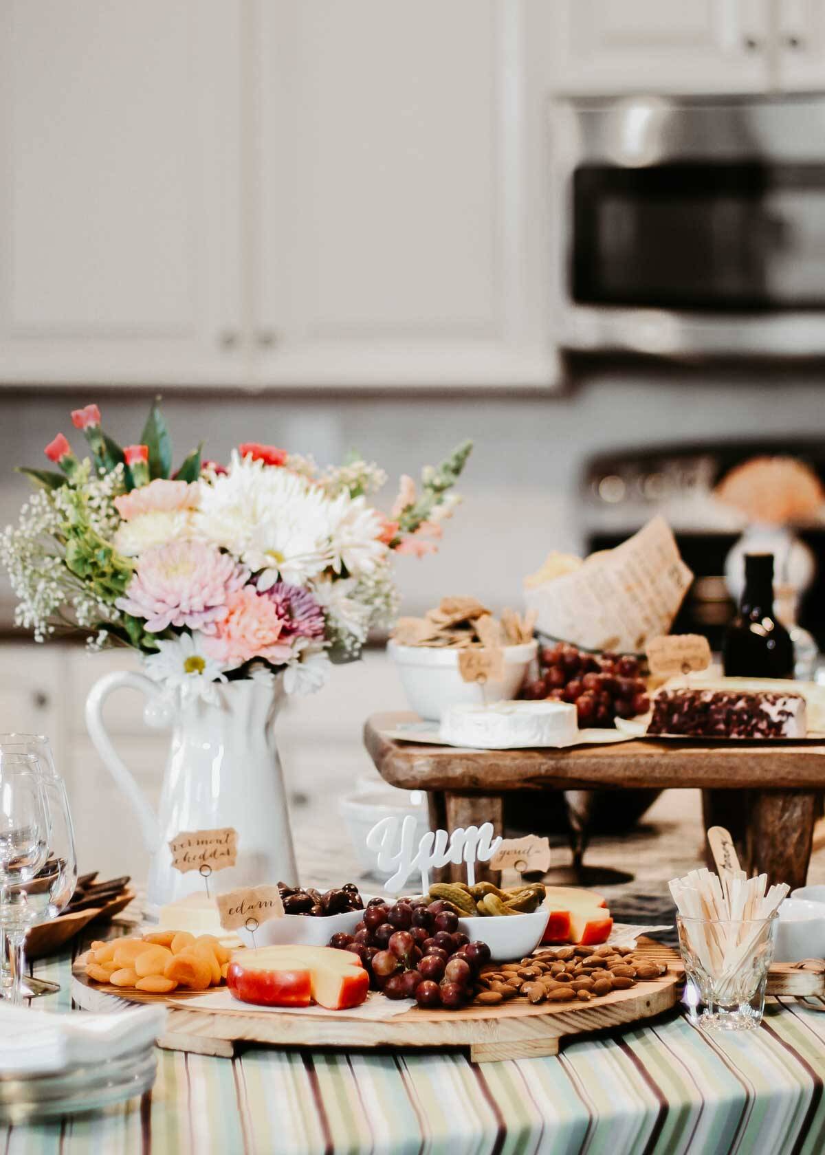 wine and cheese party foods and flowers set up on kitchen island.