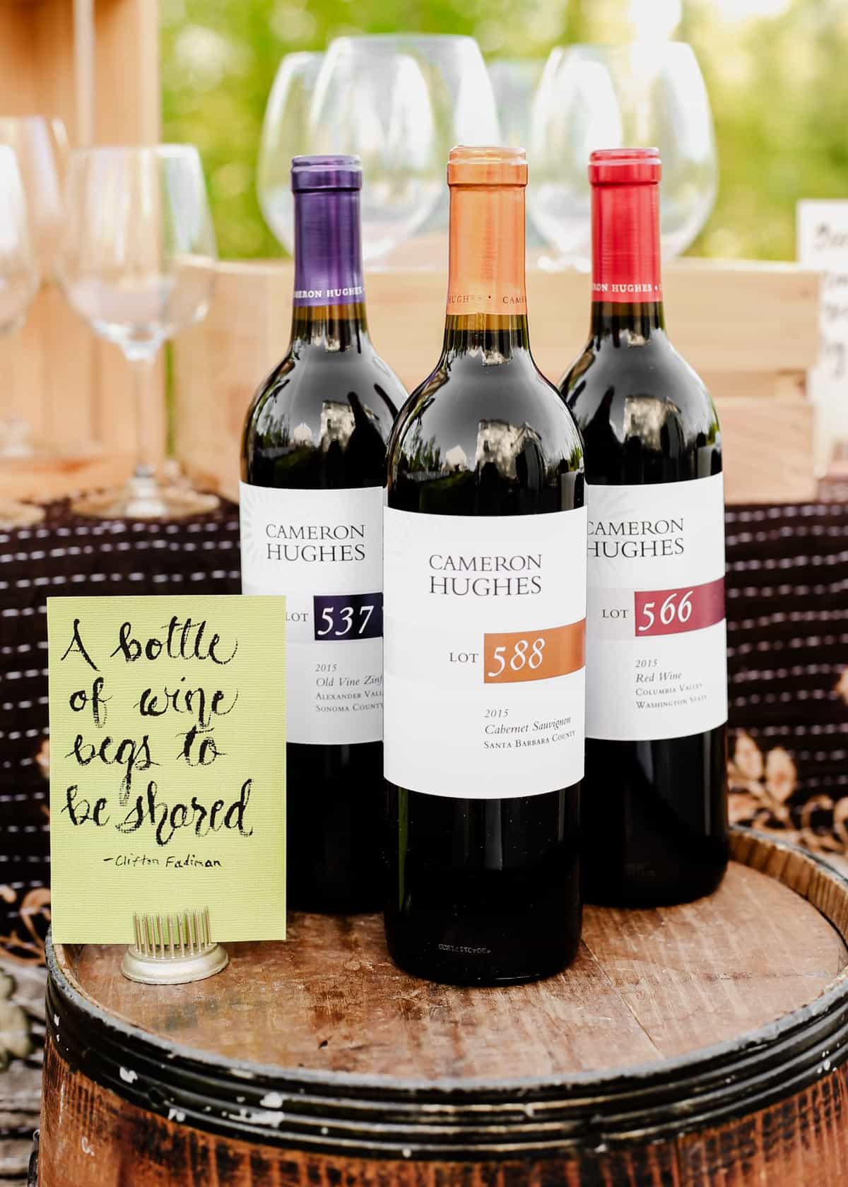 three bottles of wine on round table outdoors.