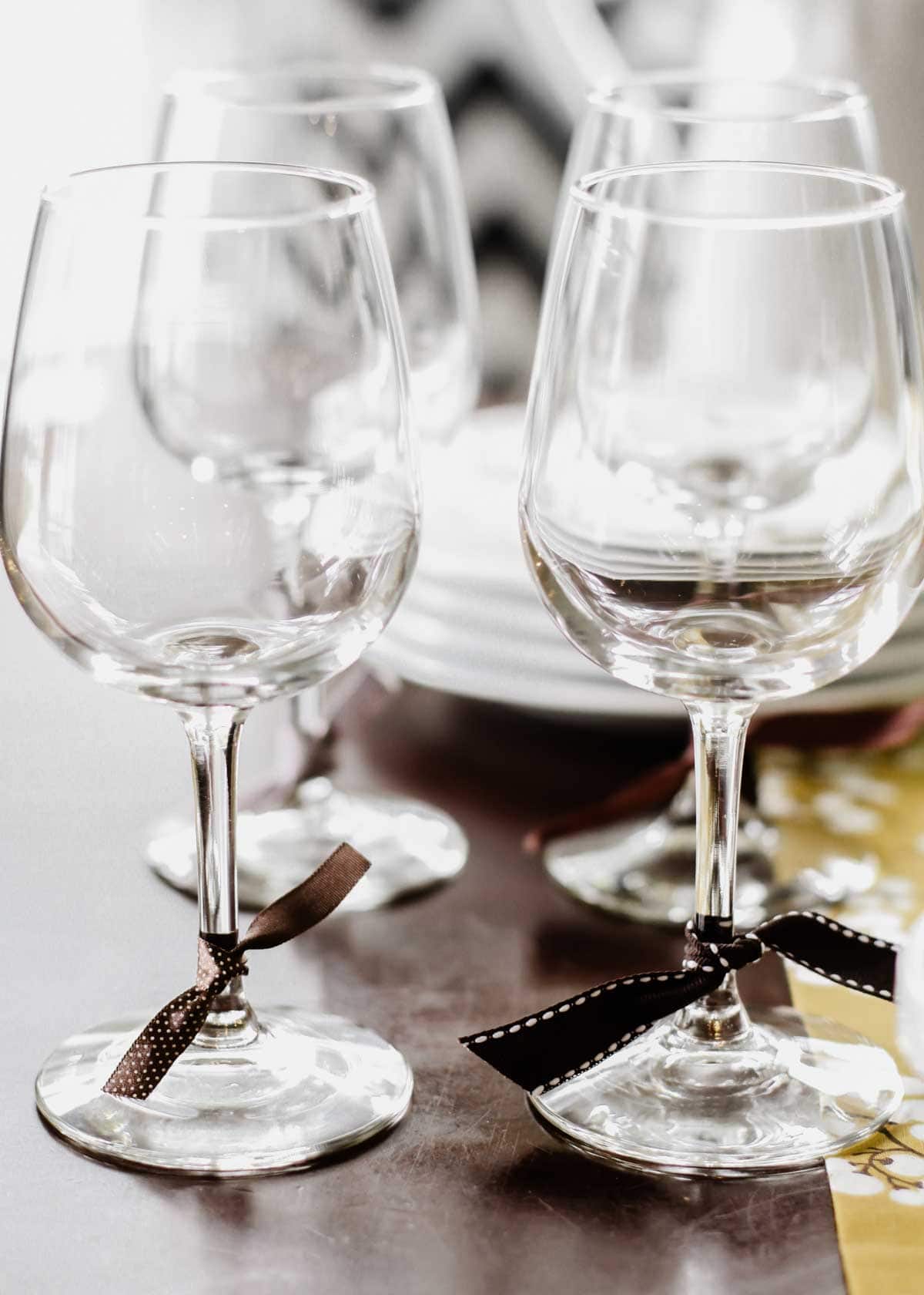 wine glasses on table, with ribbons tied around the stems.