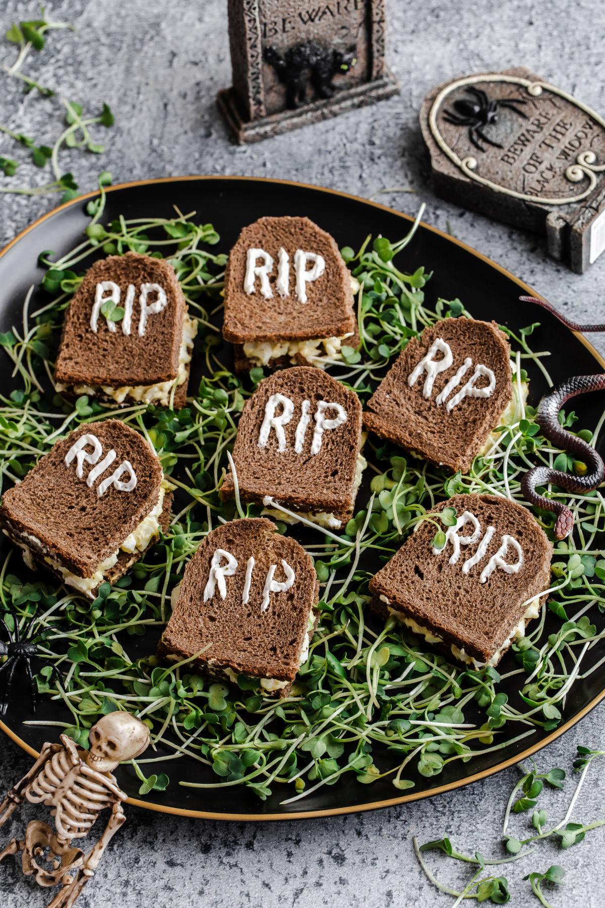 tombstone shaped tea sandwiches are the perfect savory snack at your halloween tea party, served on a bed of sprout "grass."