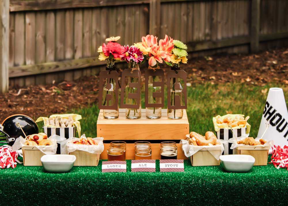 beer bar table set up outside with turf grass table cover and stadium snacks.