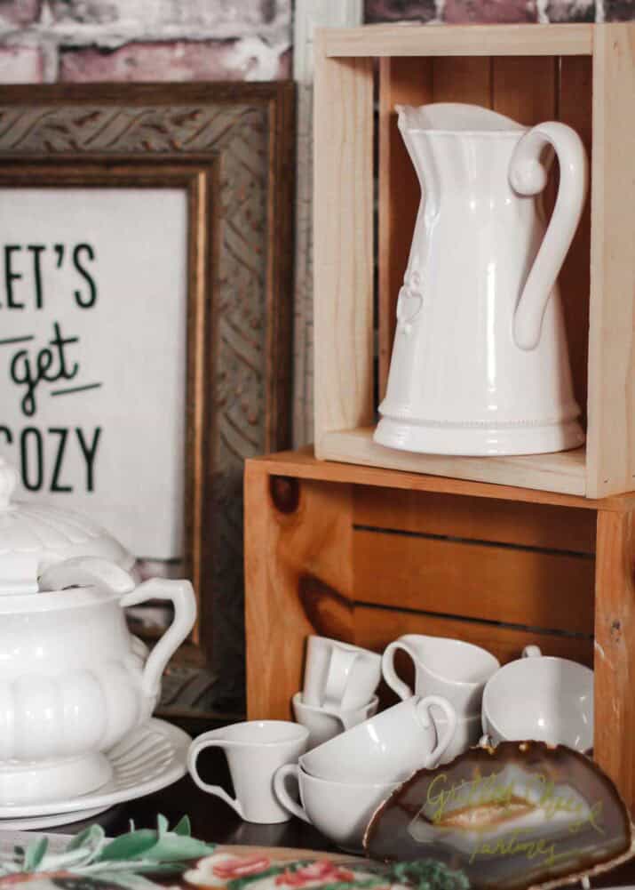 wood crates stacked on food buffet table with pitcher and cups sitting inside.