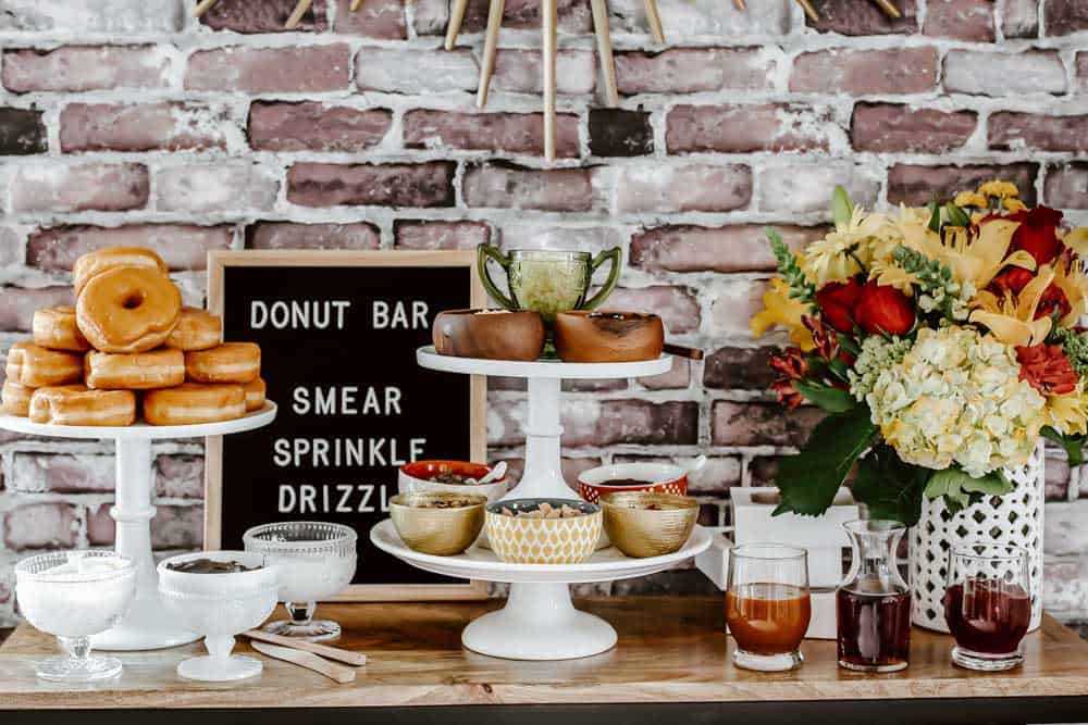 donut buffet table with several white cake pedestals for displaying food.