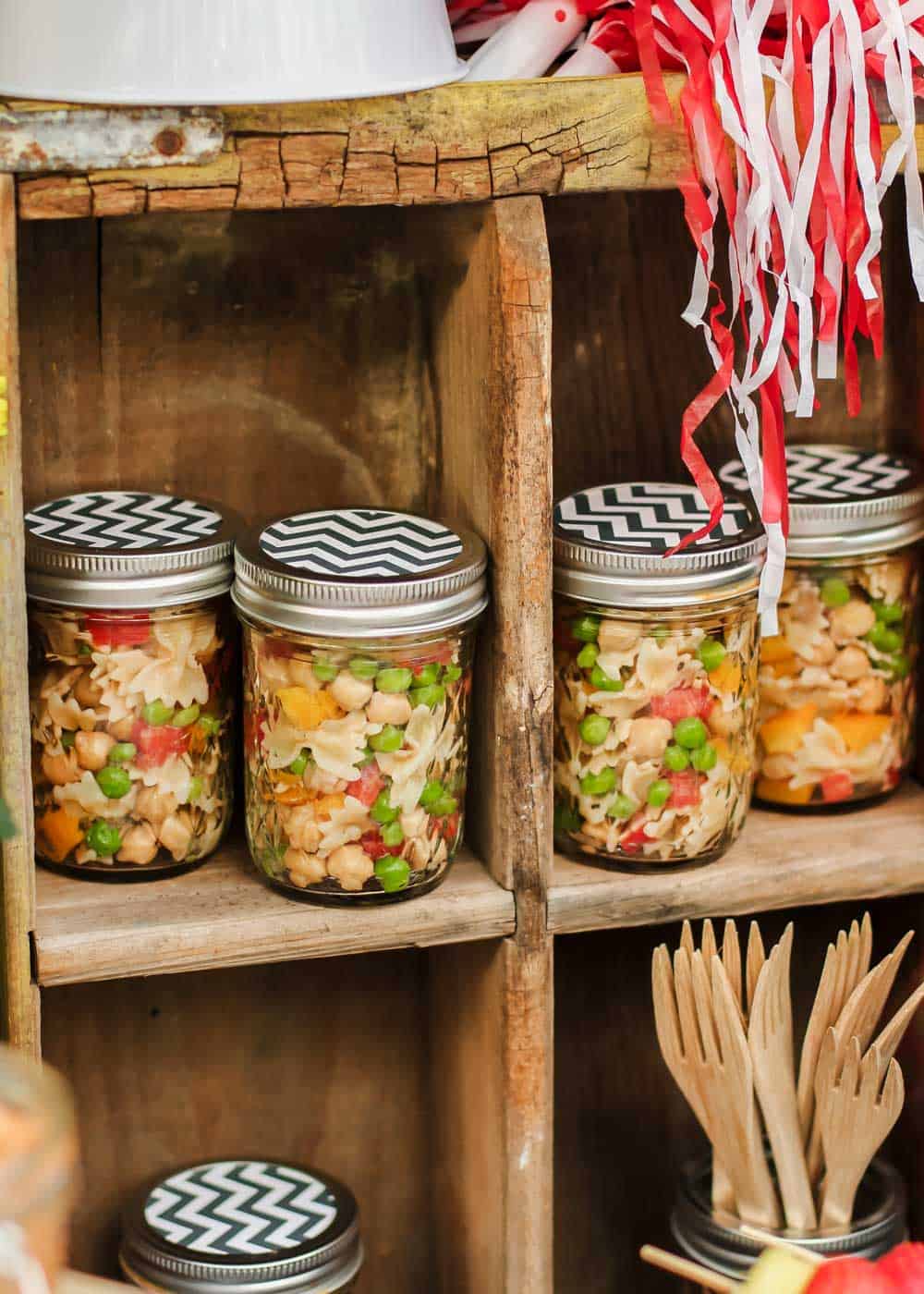 vintage soda crate on its side holding jars filled with pasta salad.