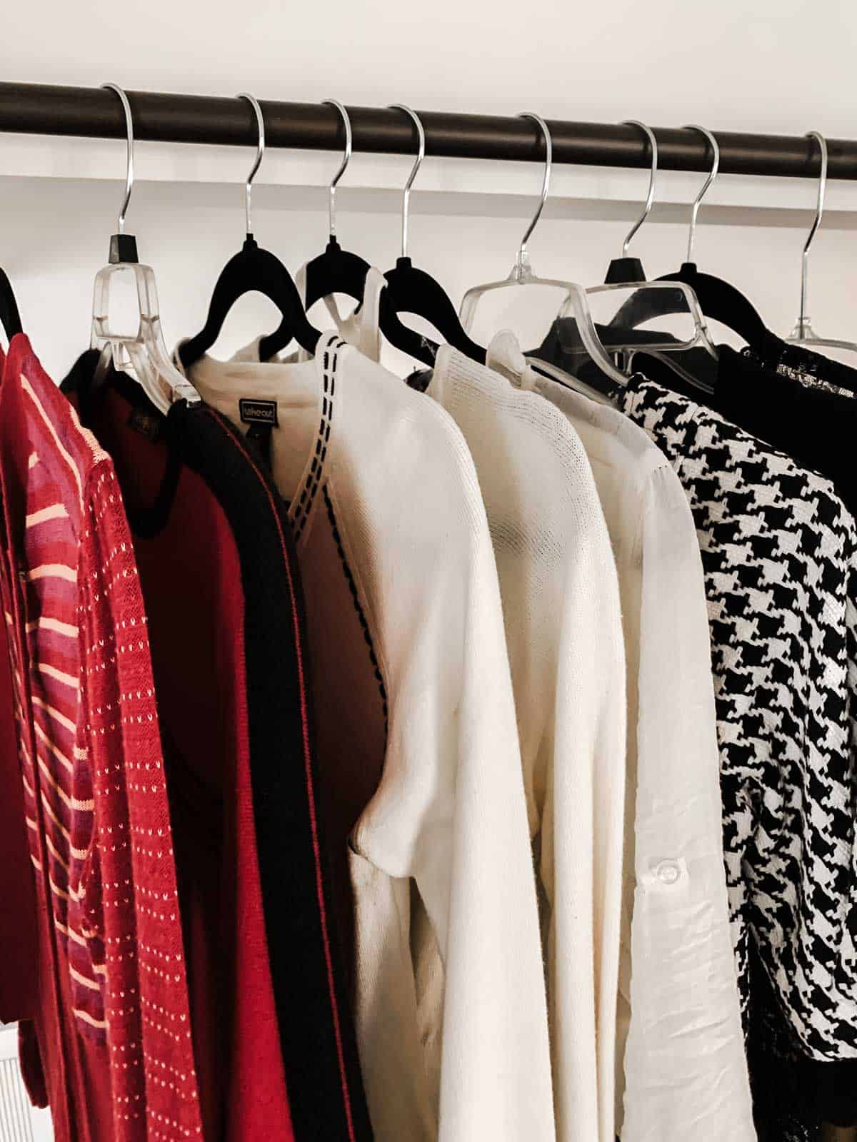 ladies shirts and sweaters hanging on a rod.