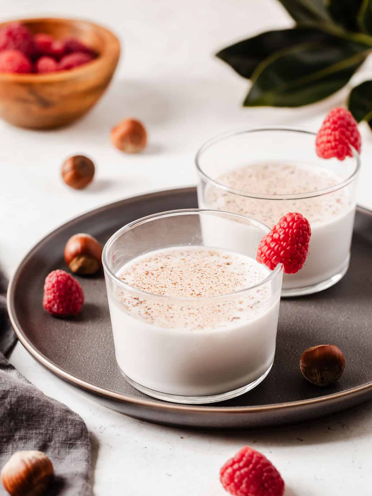 two shore glasses with creamy drink garnishes with raspberries.