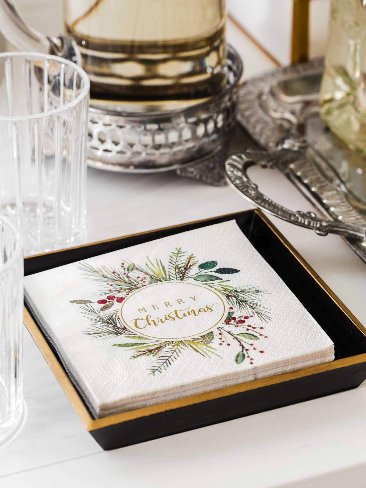 Christmas wreath cocktail napkins in square holder.