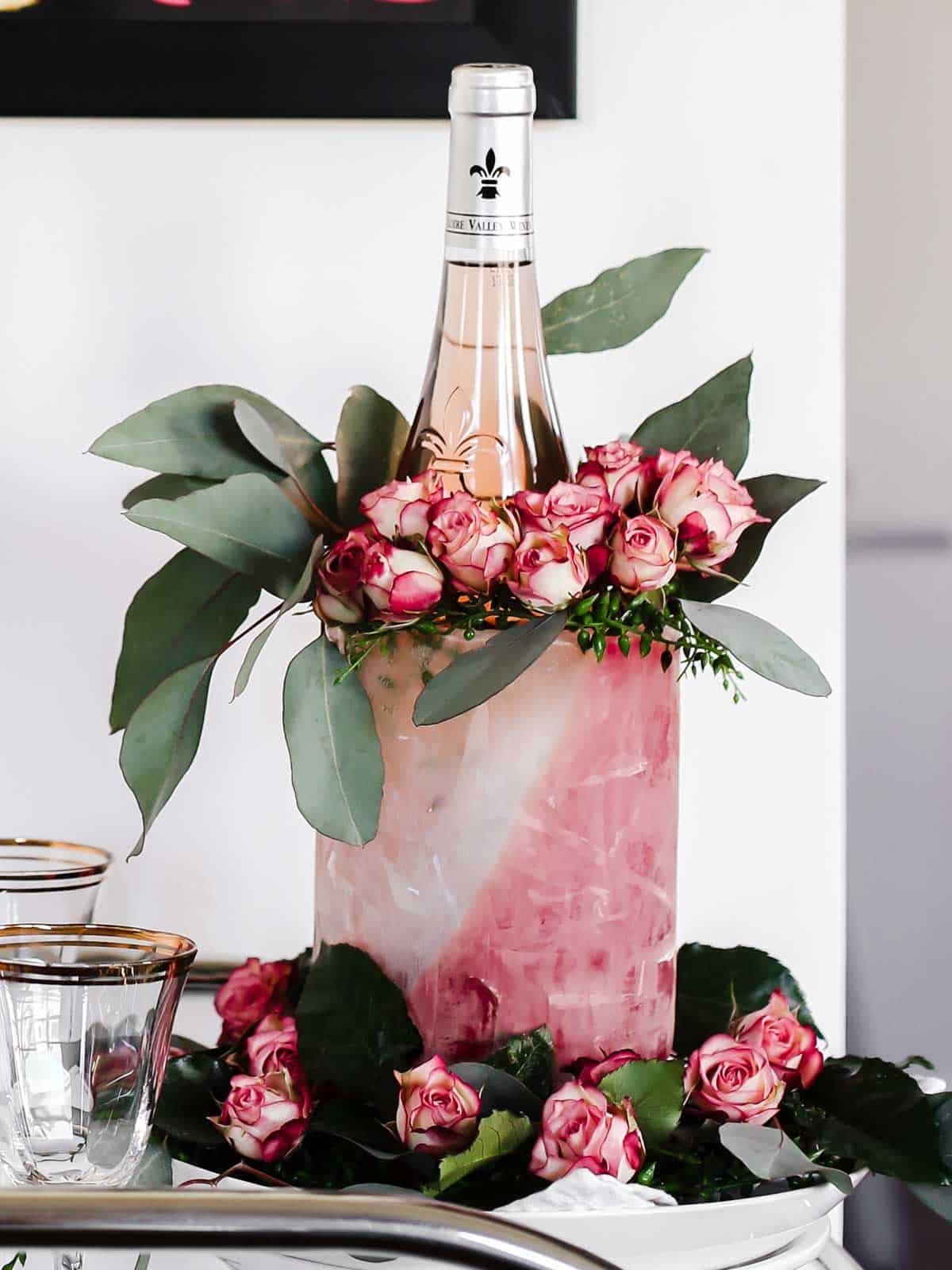 DIY ice mold for wine bottle with colored water and flower garland.