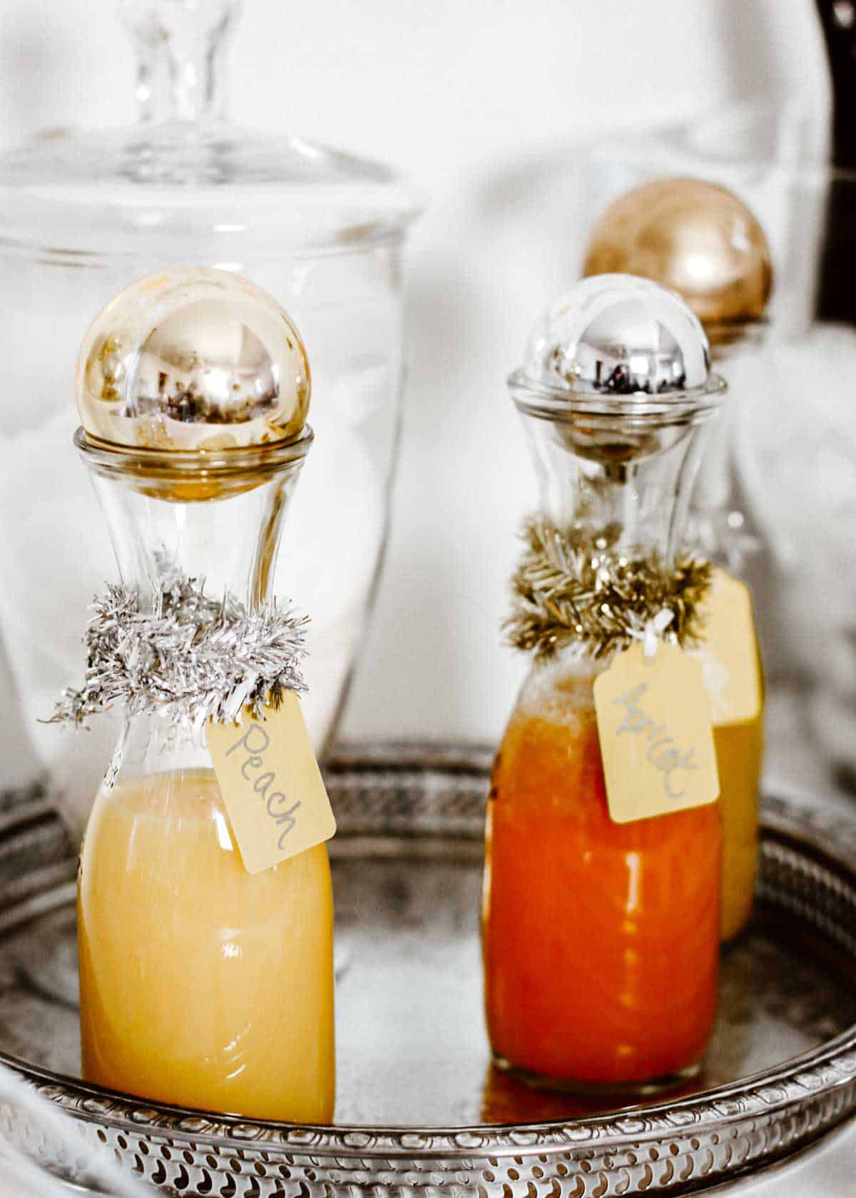 bottles of juice, topped with ball ornament for Christmas.