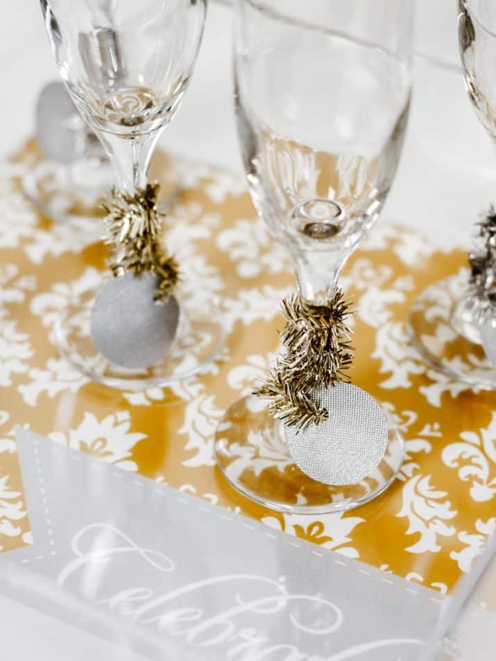 champagne flutes with Christmas tinsel wrapped around the stems.