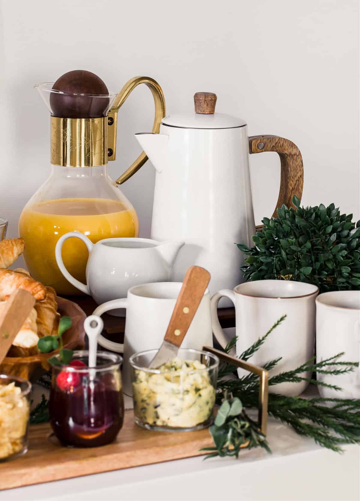 coffee pot and juice in carafe surrounded by mugs.