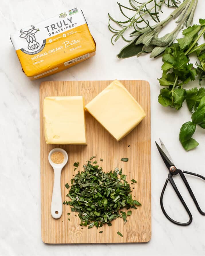 butter and fresh chopped herbs on wood board