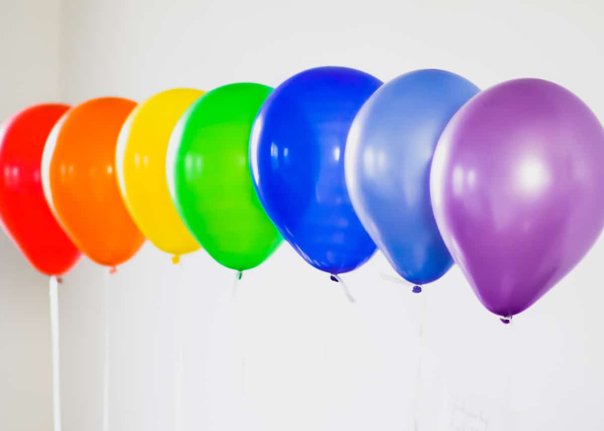 rainbow colored balloons floating in a row.