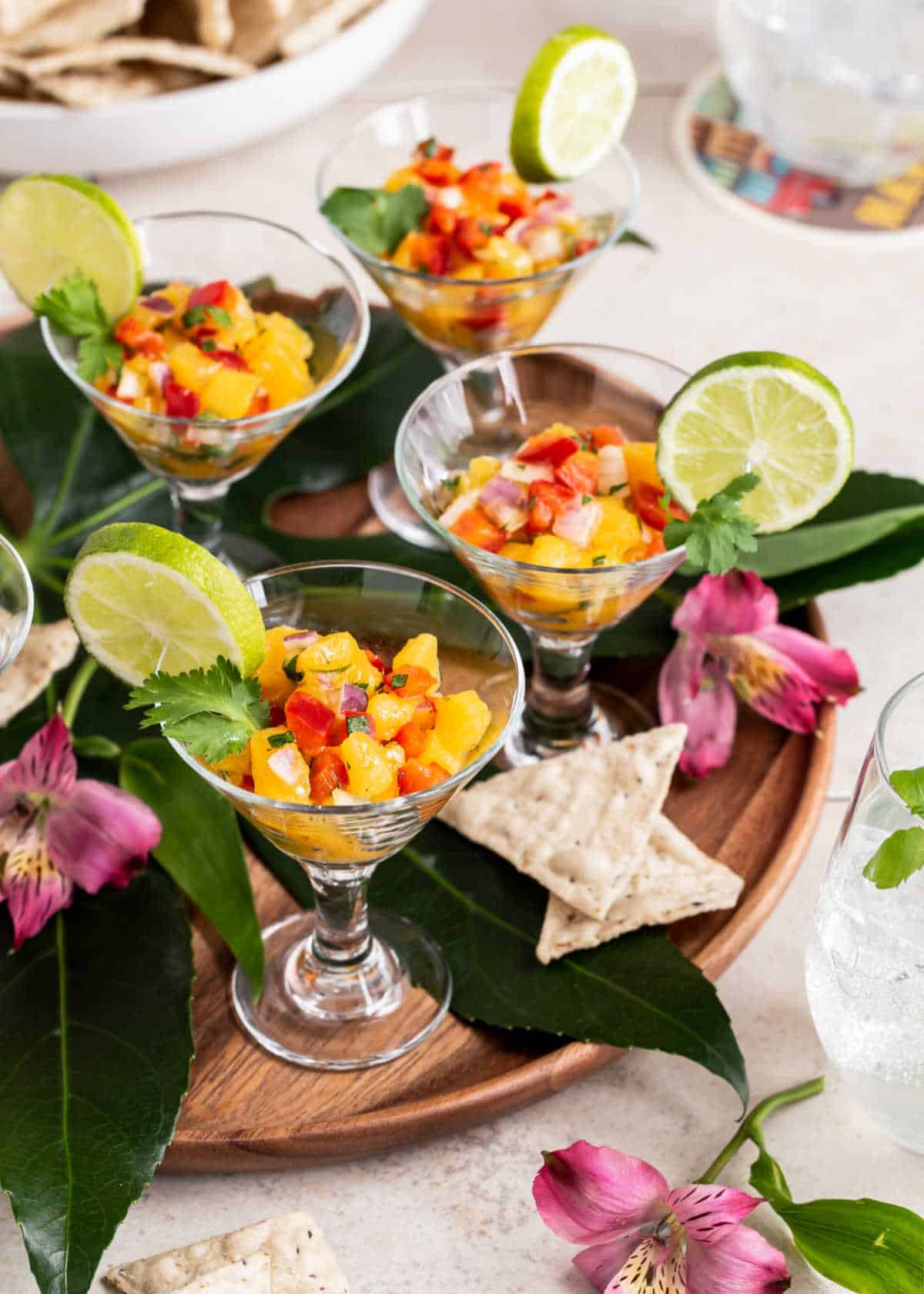 tropical salsa in mini glasses on wood tray with leaf decoration.