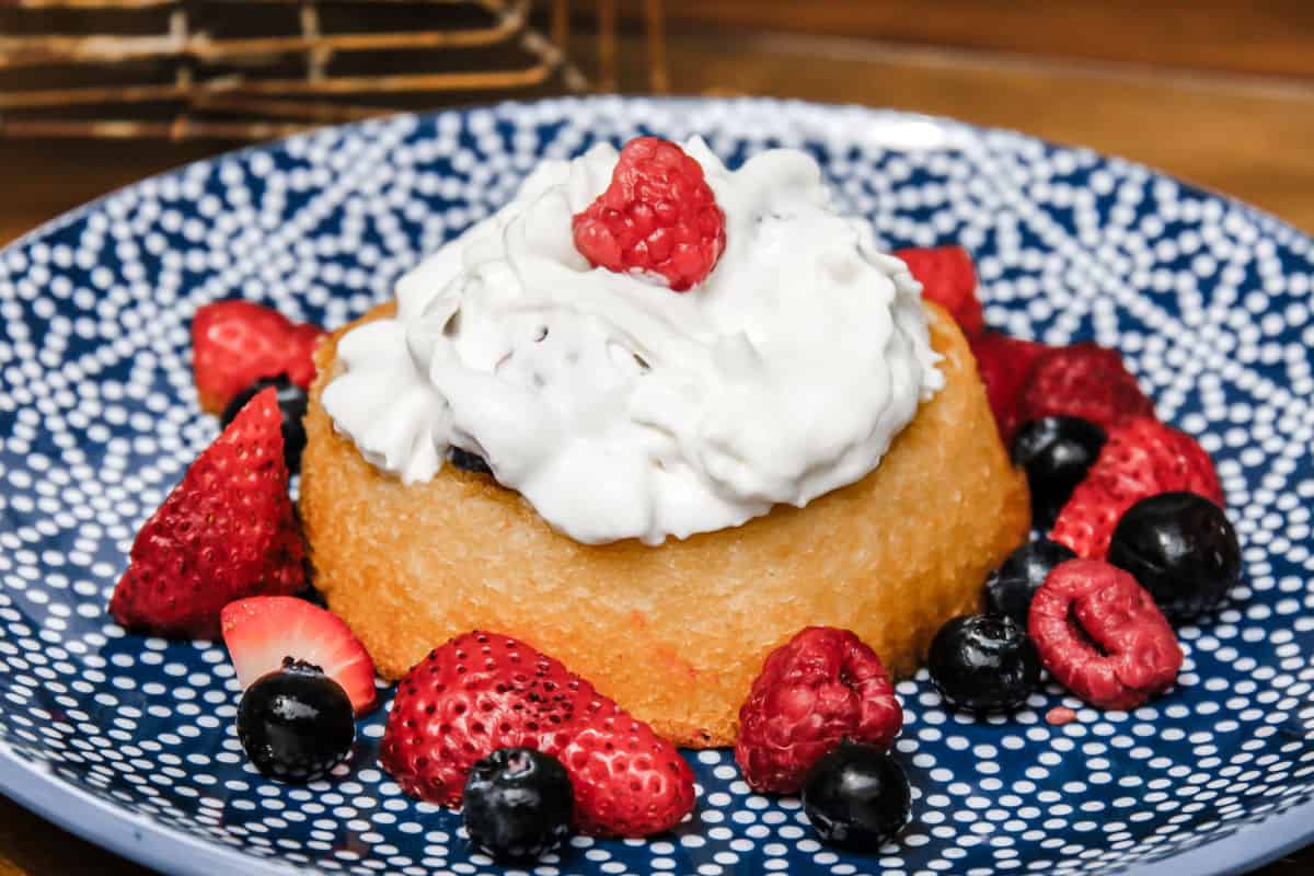 fresh berries on sponge cakes with whipped cream on top.