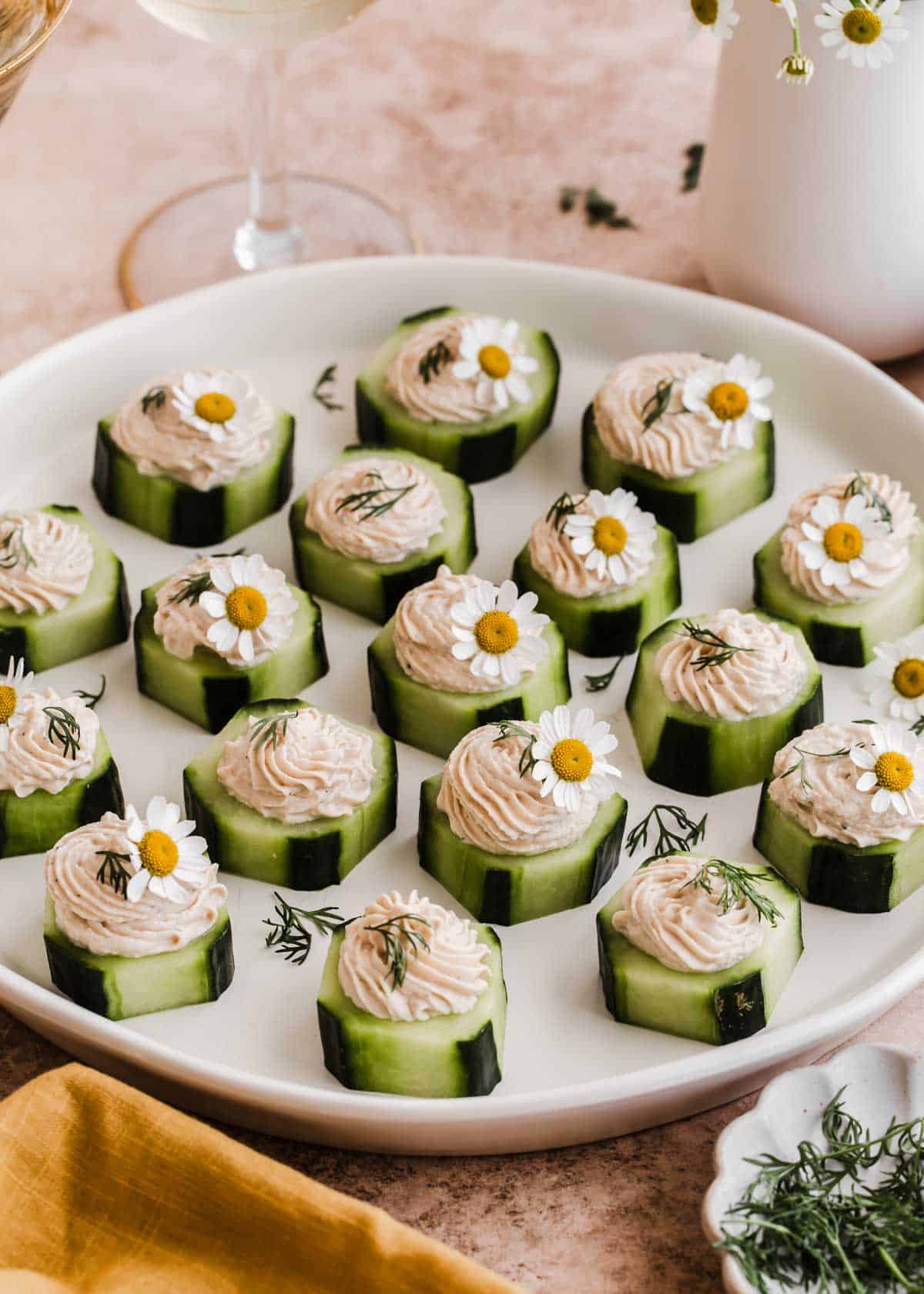 white plate filled with cucumber appetizers garnished with fresh dill and tiny white flowers.