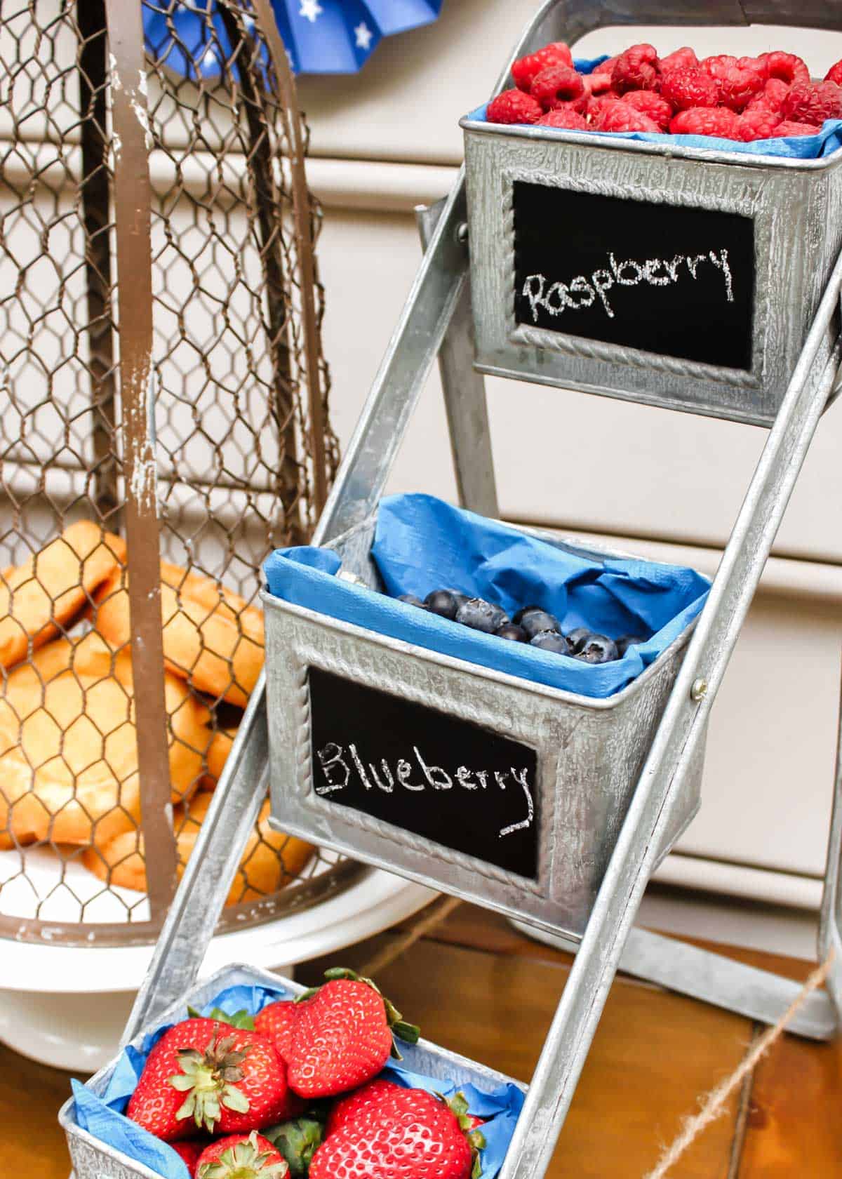 galvanized 3-tiered container holding strawberries, blueberries, and raspberries. 