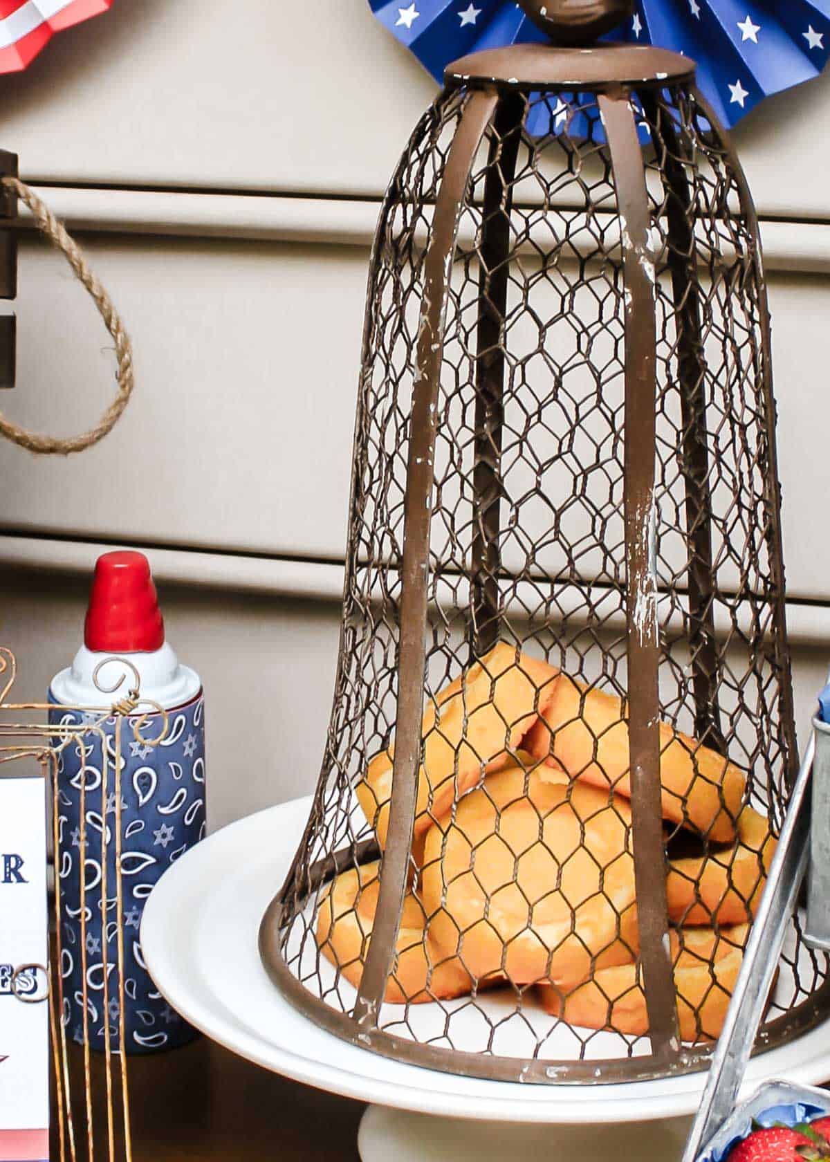 mini shortcakes piled on white plate with wire cloche overtop. 