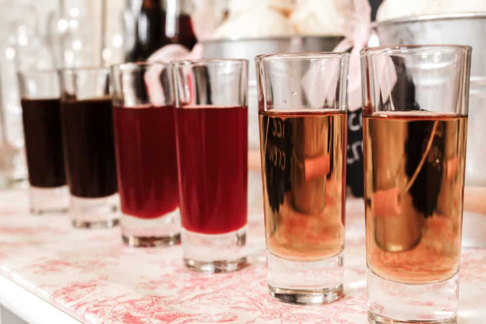 flavored syrups in tall shot glasses, lined up on table.