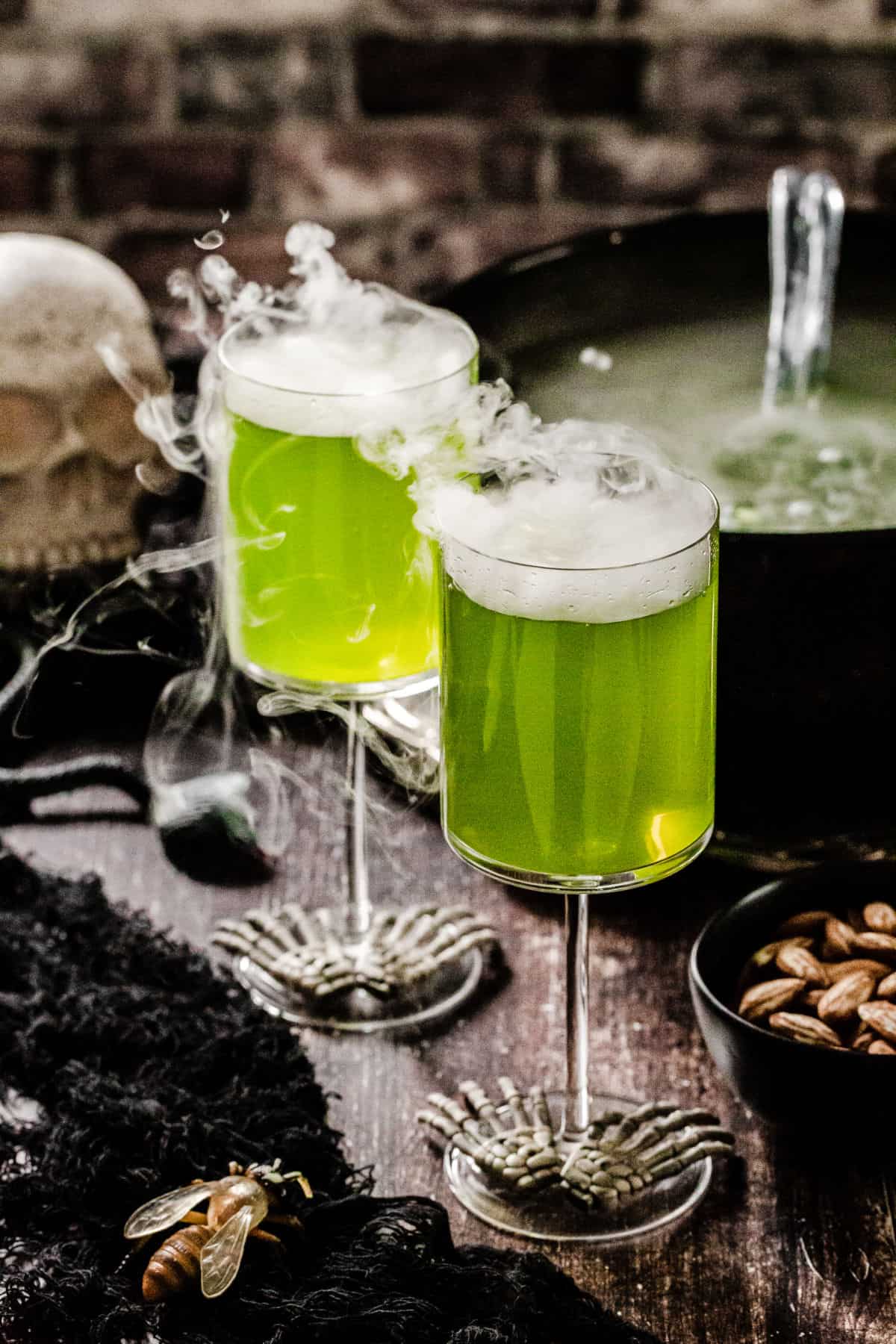 two wine glasses with green drink and dry ice fog