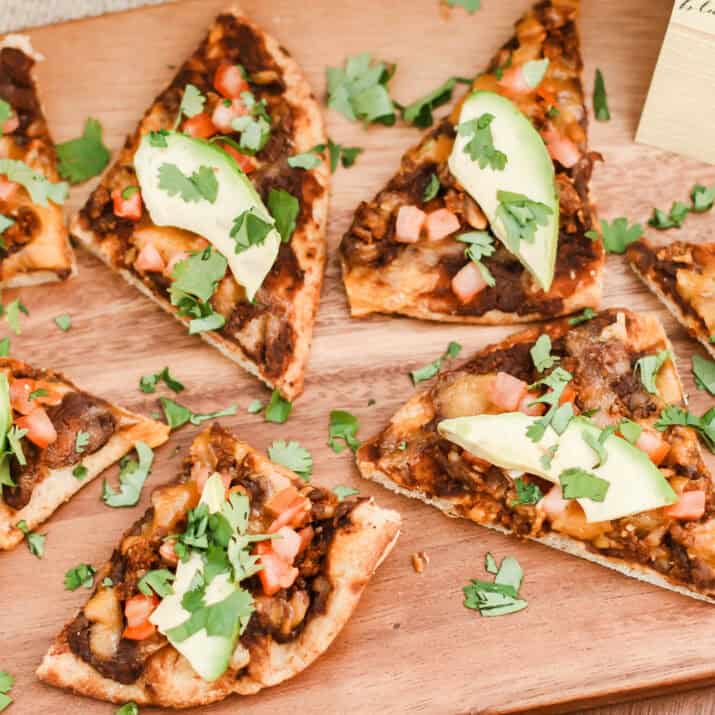 pizza slices with black beans, chorizo, tomato and avocado.