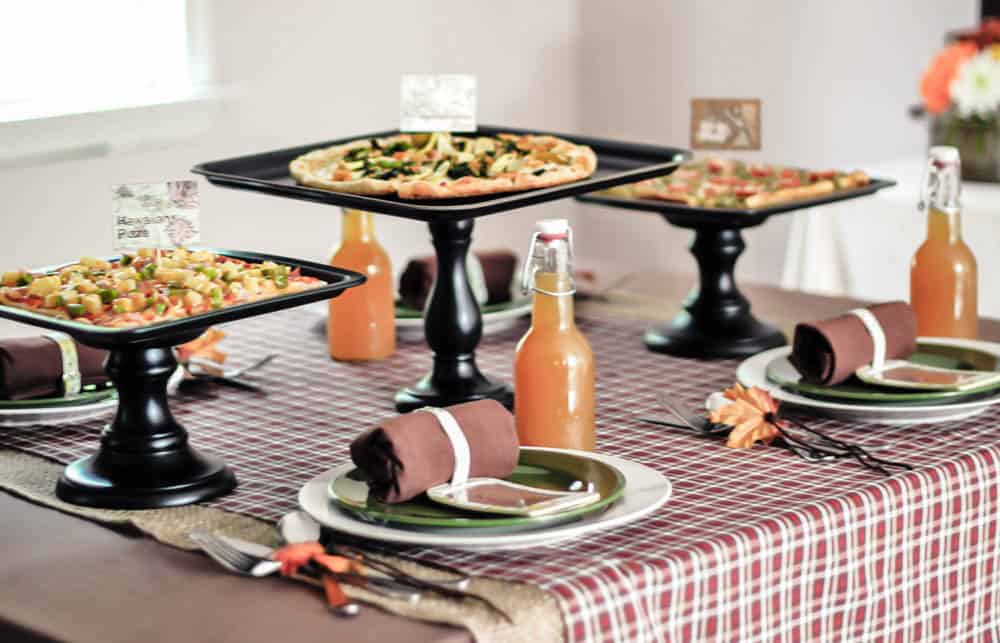 dining table set up with three pizzas on pedestals.