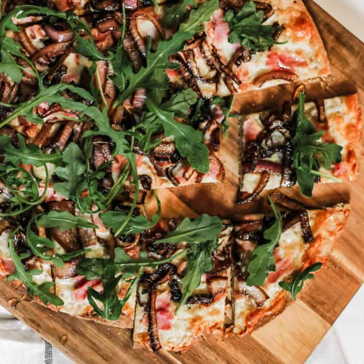 pizza with ham, onion and arugula.