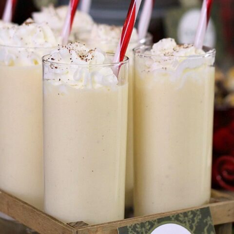 eggnog punch in glasses with red striped straws.