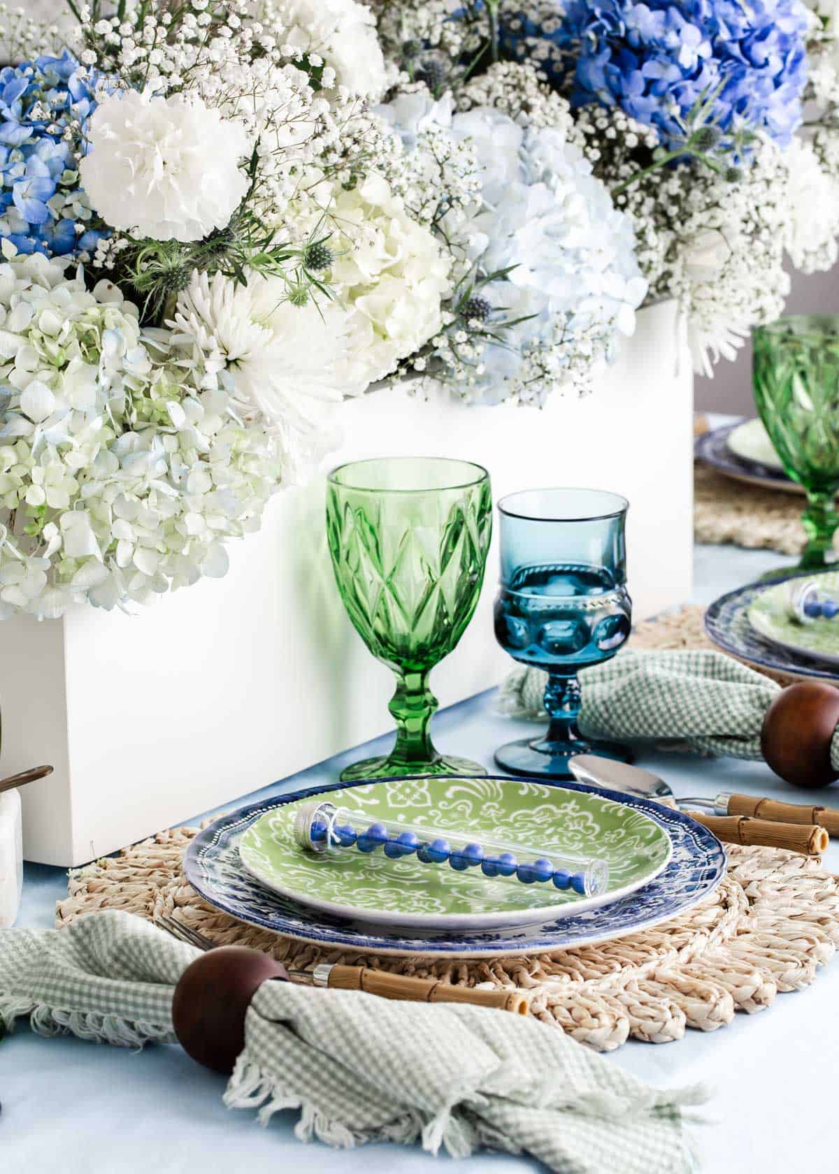 spring tablescape with blue and green dishes and glasses on top of blue tablecloth.