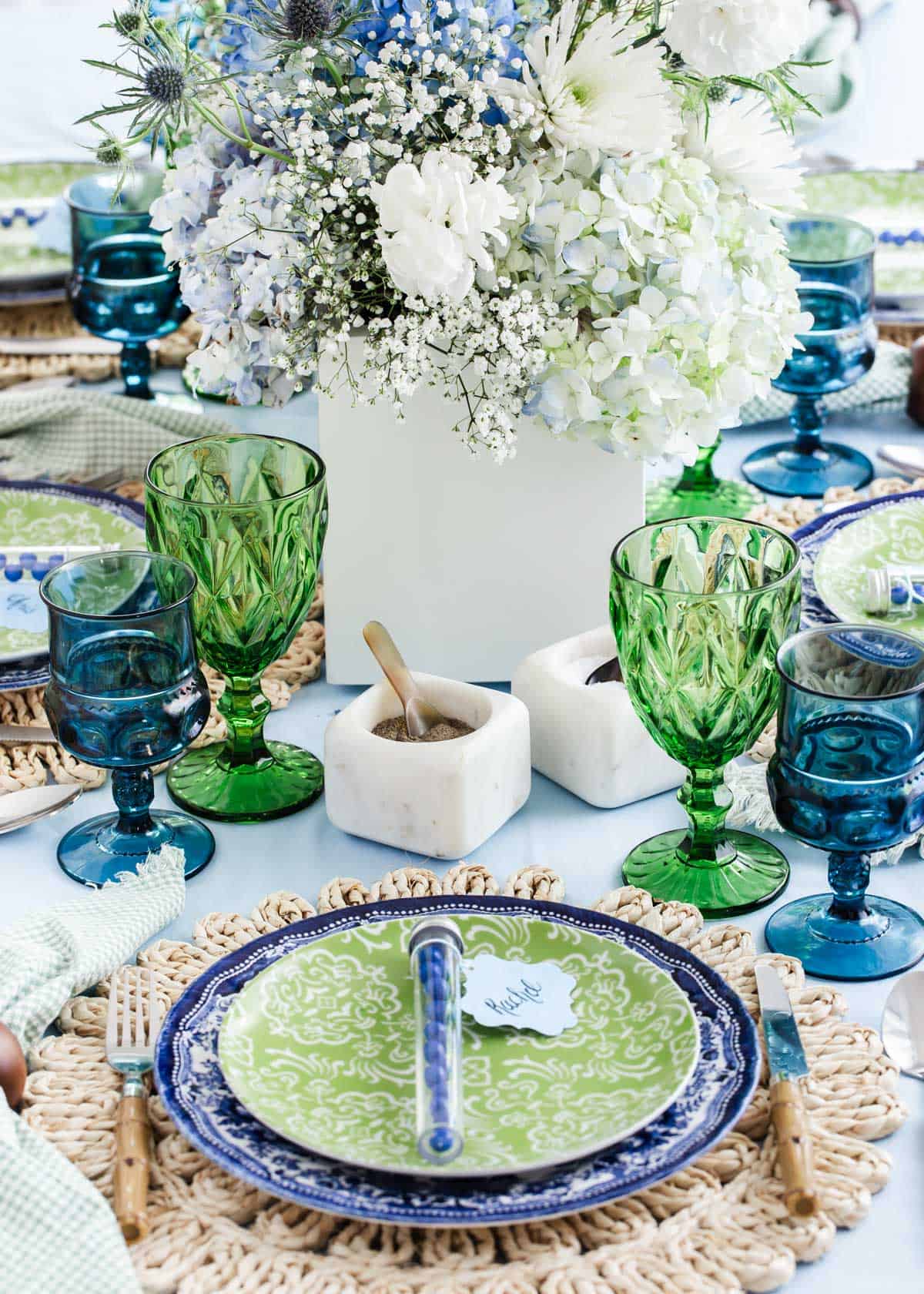 spring tablescape with blue and green dishes and glasses on top of blue tablecloth.