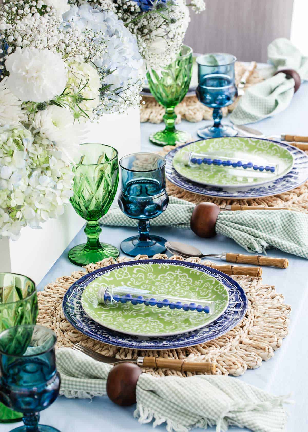 tablescape with blue and green decor and settings with hydrangeas centerpiece.