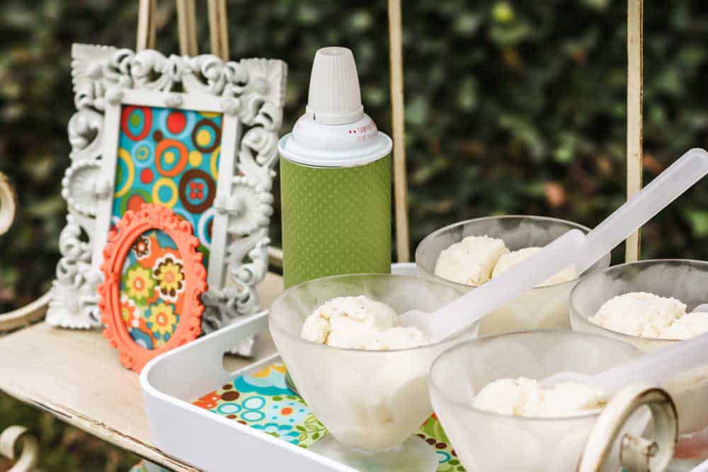 shelf set up outdoors, with tray of ice cream in bowls and whipped cream can.