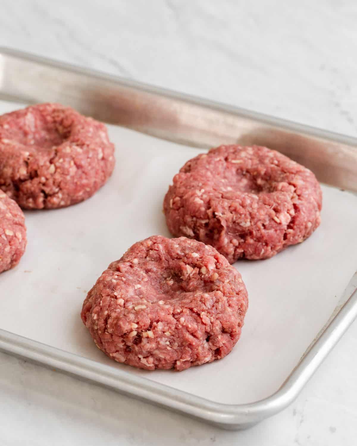 raw hamburgers formed and placed on sheet pan.