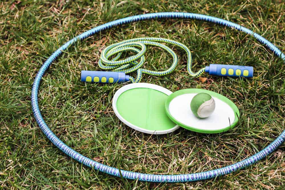 hoola hoop, jump rope, and velcro ball toss sitting on lawn.