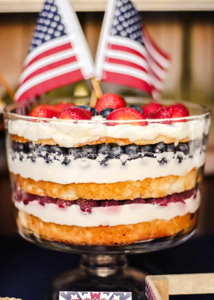 trifle with layers of cake and white cream with red and blue berries.