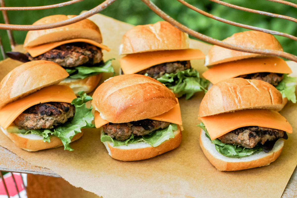 slider burgers on buns with lettuce and cheese, for outdoor cookout.