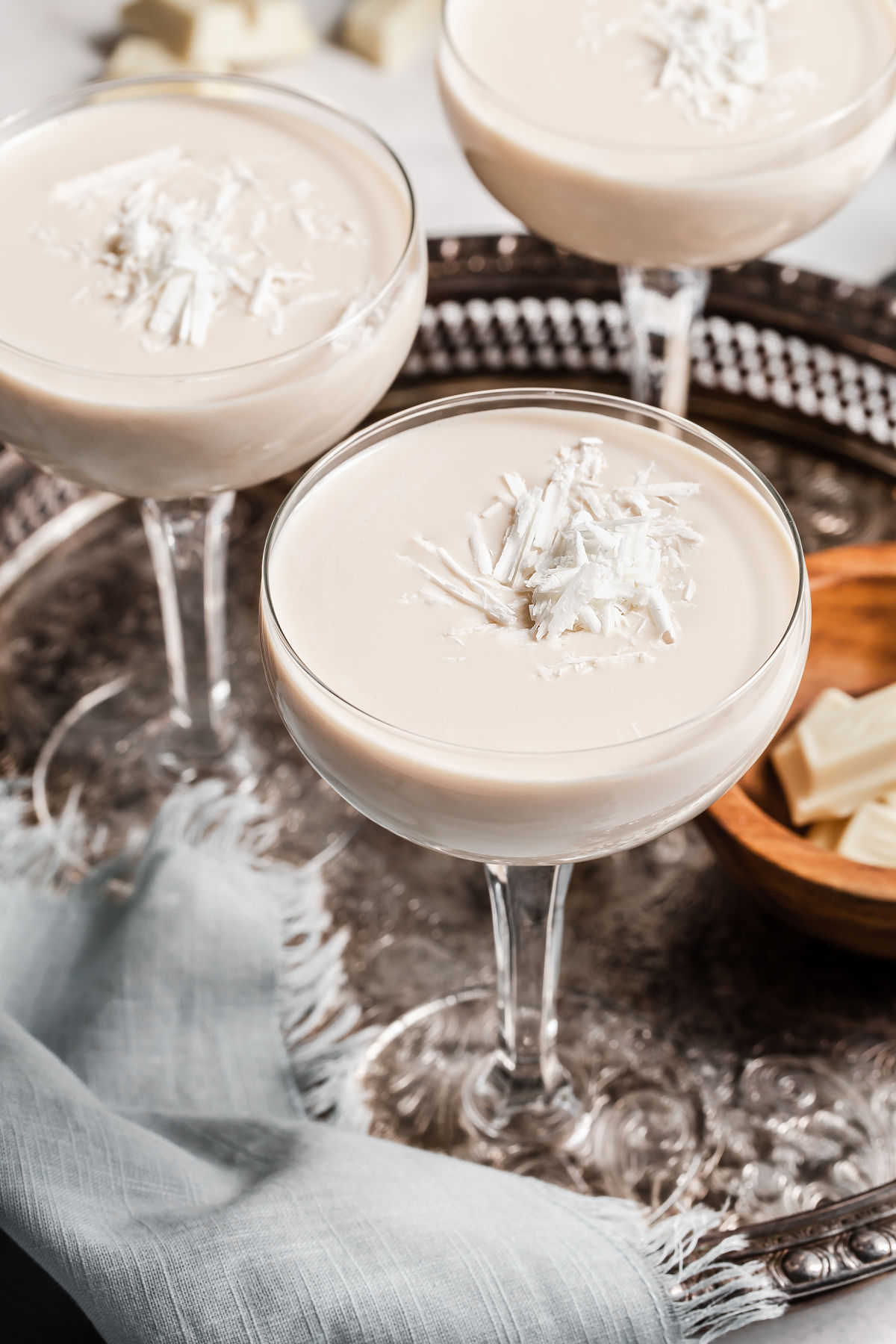 three coupe glasses of white chocolate martinis on silver tray