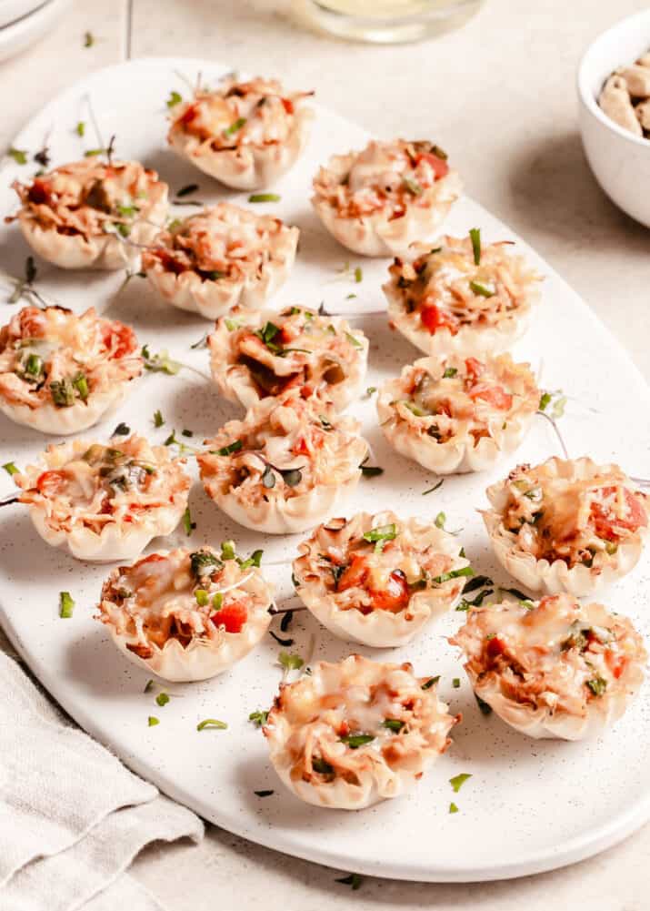 phyllo cups filled with chicken and vegetable and cheese mixture, on oval tray.