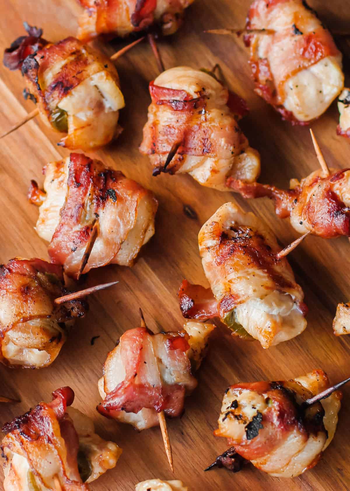 bacon wrapped chicken on toothpicks on wood board.