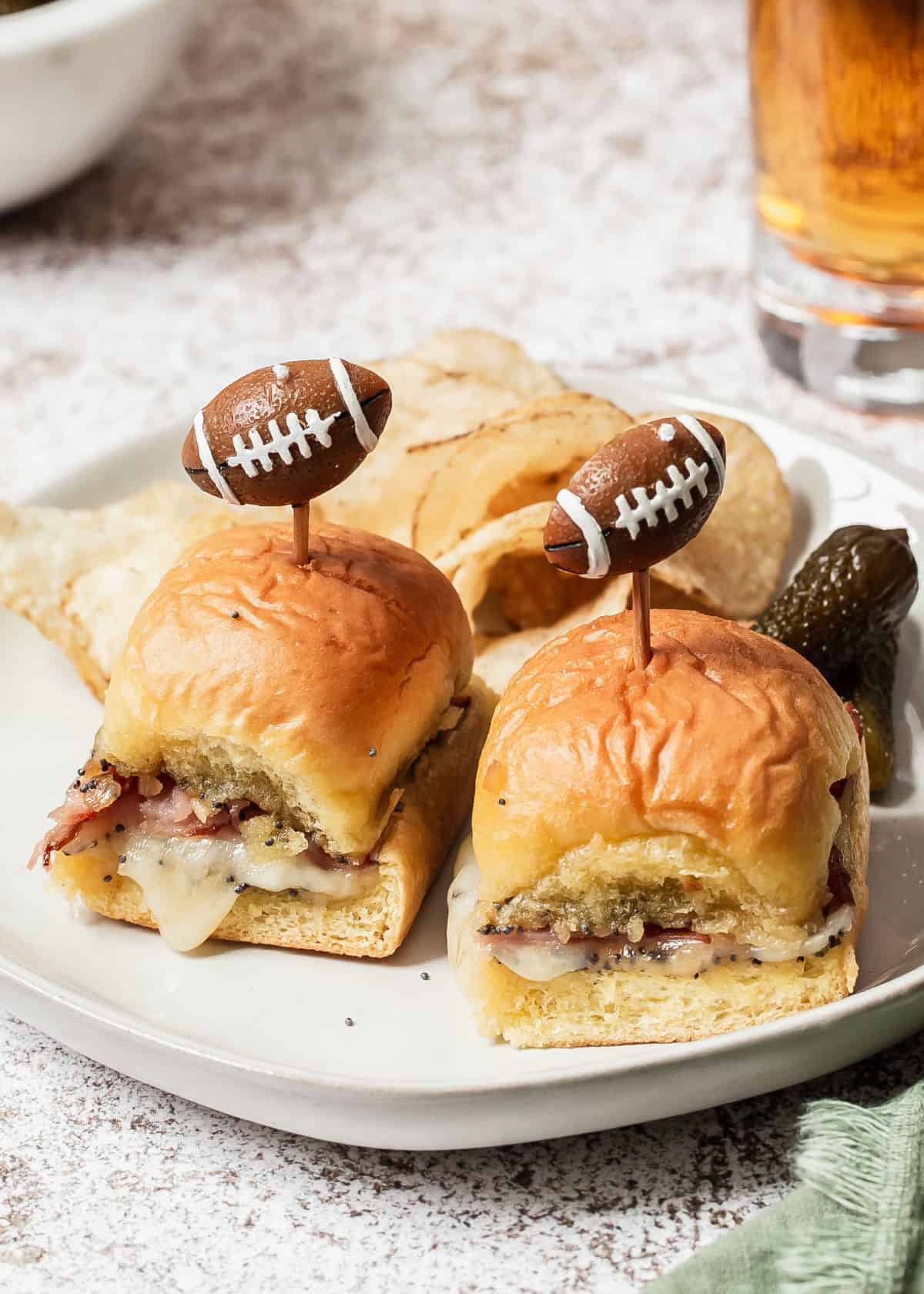 small party sandwiches with football themed picks, on plate with chips and beer.