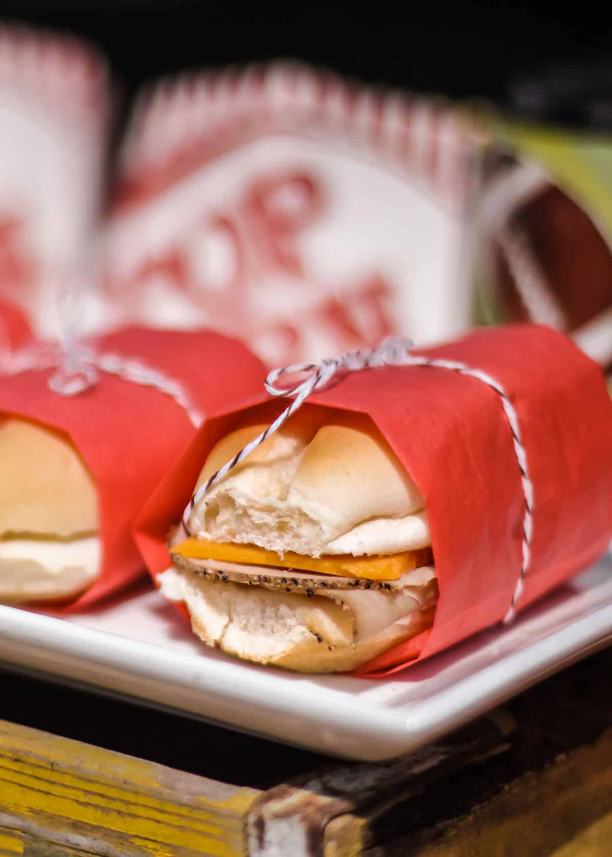 turkey and cheese sandwiches wrapped in red paper and tied with string.