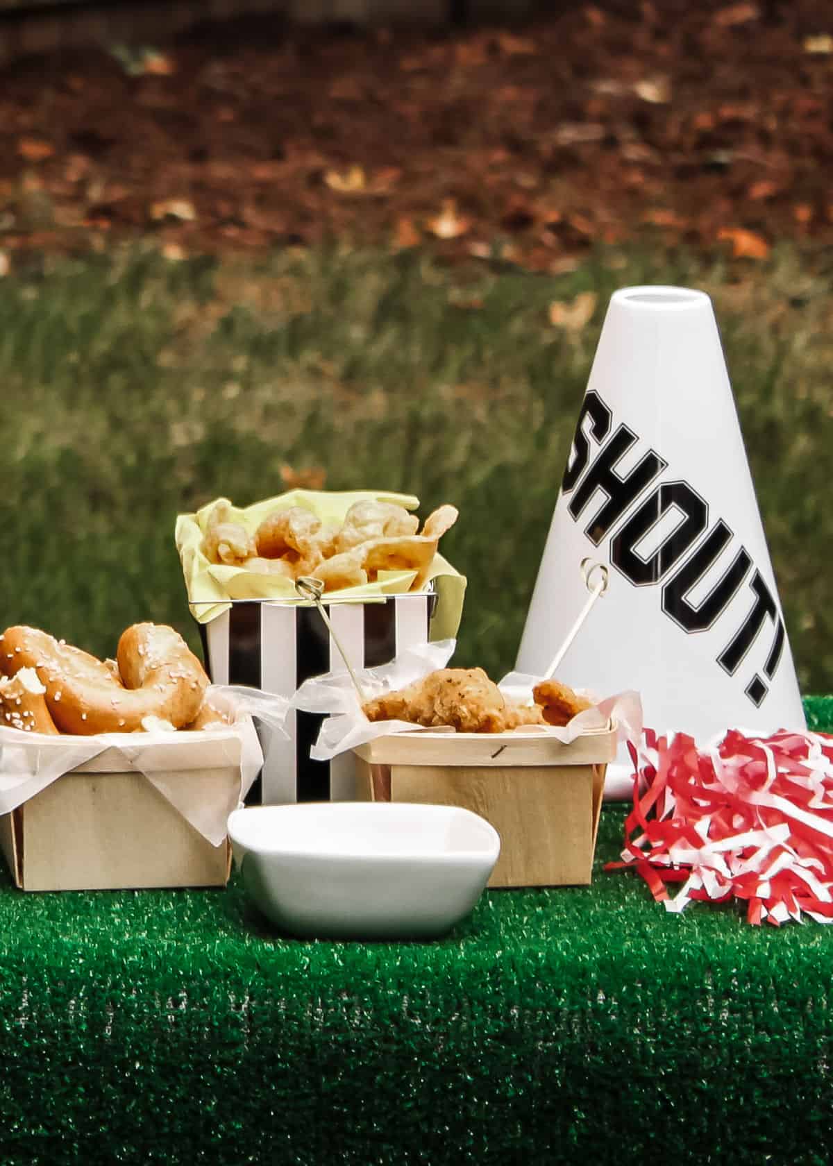 football party snacks on green turf with pompom and megaphone decoration.