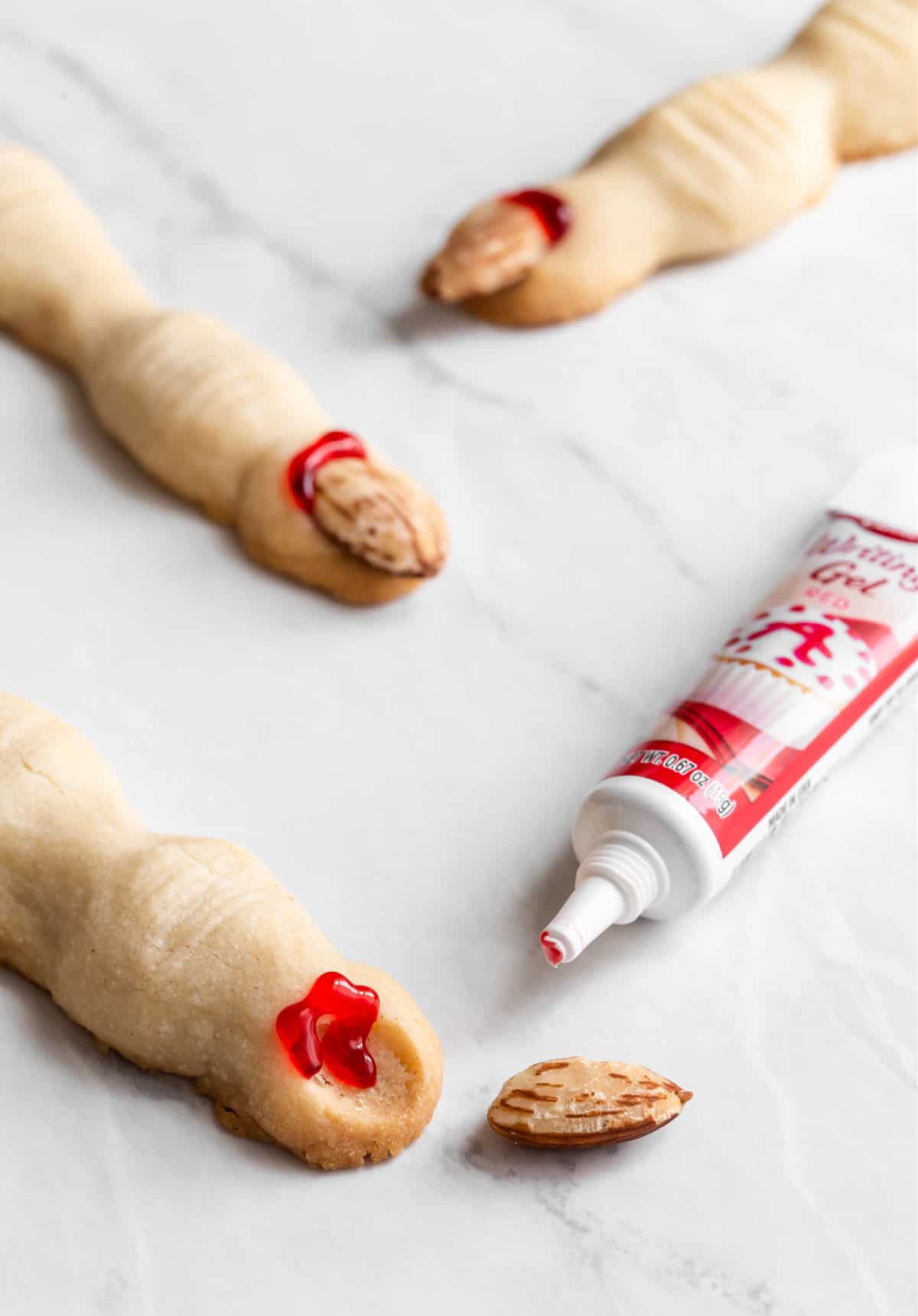 adding almond nails to finger cookies with red decorator gel