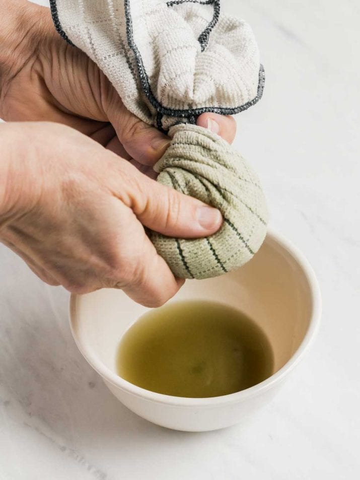 juice being rung out of spinach in a cloth.