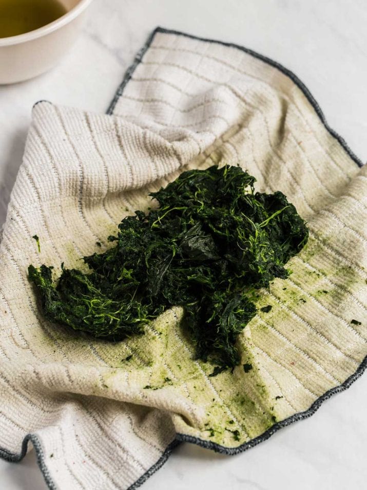 prepared spinach in a cloth on counter.